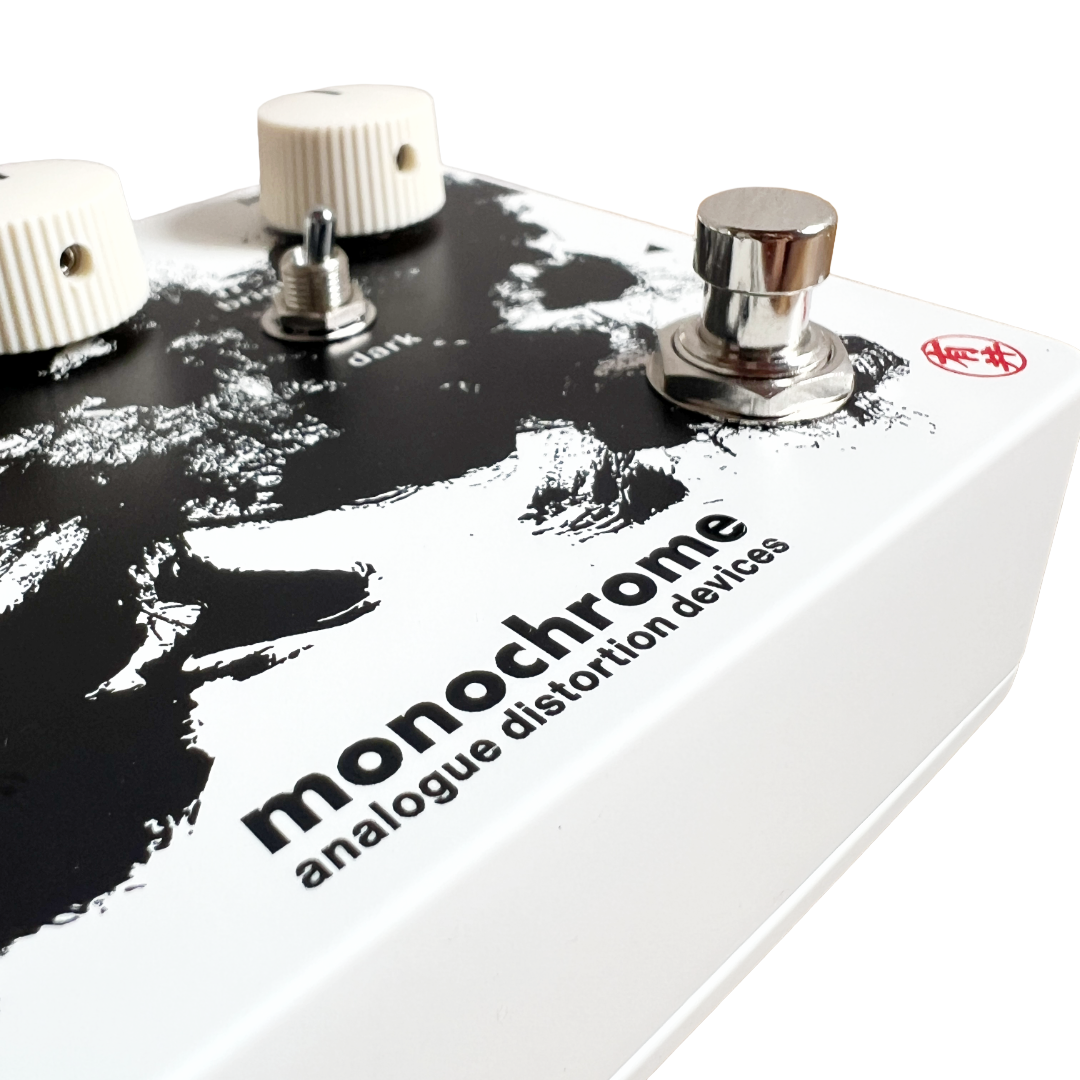 Guitar effects pedal with 'monochrome analogue distortion devices' text on a white background